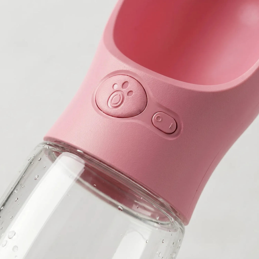Detalle del dispensador con botón e icono de huella en la botella bebedero portátil para mascotas, diseño antiderrame Chile